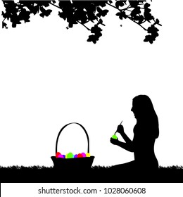 Girl coloring Easter eggs sitting in park in spring silhouette