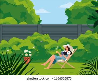 Girl with a cup reads a book while sitting on a deck chair in the garden.