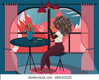 Girl with curls alone drinks coffee in front of a window outside the city, admiring the mountains at sunset