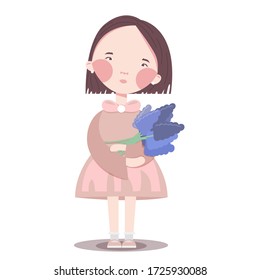 A girl with dark hair in a pink dress holds purple flowers in her hands and looks at them.