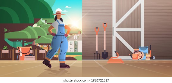 girl farmer in uniform with garden and farm tools gardening equipment near wooden barn doors eco farming agriculture concept horizontal full length vector illustration