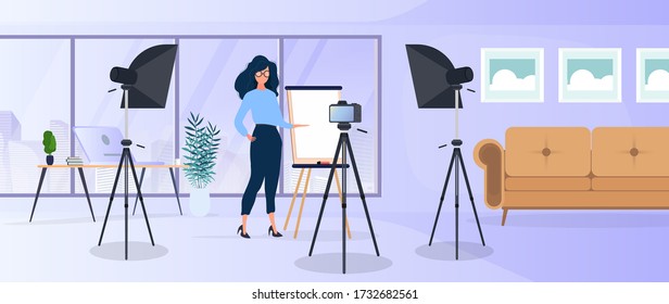 La chica está haciendo una presentación frente a la cámara. El profesor imparte una lección en línea. El concepto de blogs, capacitación en línea y conferencias. Cámara en un trípode, softbox.
