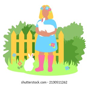 The girl is holding a white bunny in her arms. Fence, bushes in the background. Green grass spring landscape. Rabbit farm. Fluffy pets.