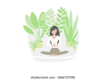 Girl with long black hair, white tshirt and brown pants, in lotus position doing yoga between many green plants in pots. Green urban jungle bubble. Crazy plant lady. Staying home and relaxing.