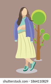 girl with long brown hair wearing a purple sweater and long yellow skirt standing in front of a tree