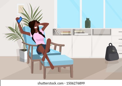 girl lying on armchair african american woman using smartphone taking selfie photo modern living room interior flat full length horizontal