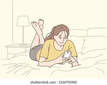 A girl is lying on the bed and looking at the phone. hand drawn style vector design illustrations. 