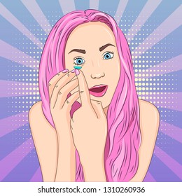 The girl with pink hair inserts, puts contact lenses in the eye. Pop art background. Imitation of comics style. Vector illustration