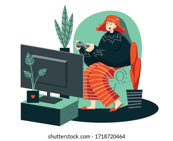 A girl plays a video game on a game console. A female gamer with a joystick in her hands plays on a console with a large monitor in a cozy home environment while sitting in a large armchair.