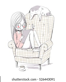 Girl reading a book in an armchair with a cat