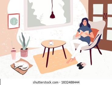 The girl is reading a book, engaged in self-development in quarantine due to the coronavirus. Female enjoying recreation and selftime. Interior with stylish furniture  in Scandinavian hygge style