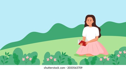 Girl reading a book on the grass.