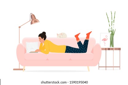 A girl reads a book on the couch.