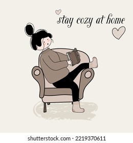 girl reads a book in warm clothes in an armchair.