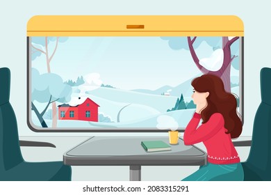 A girl in a red sweater looks out the window at the winter landscape. Traveling by train. A view of the village landscape with houses, forest and fields. A ride in a train carriage for the New Year