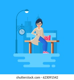 The girl sits on the bench and looks at the  wristwatch. Woman on the background of the city. She is waiting for the arrival of something. 