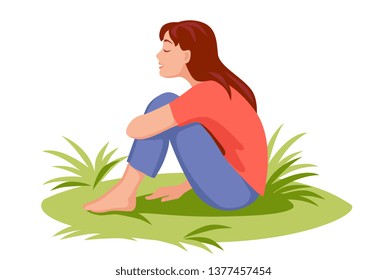 girl sits on the grass barefoot exposing her face to the rays of the spring sun