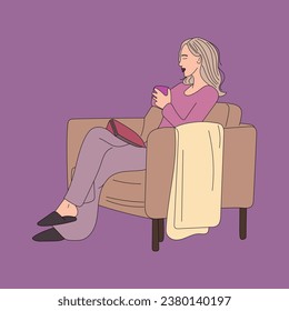 The girl is sitting in an armchair with a book and a cup