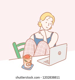 A girl is sitting comfortably at the table and looking at the computer. hand drawn style vector design illustrations.