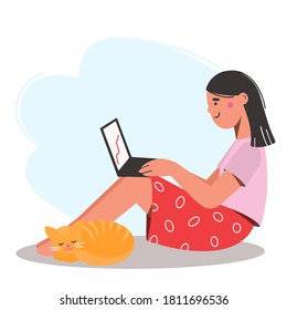 Girl is sitting on the floor with a laptop on her lap. Red cat is lying nearby. Work from home.