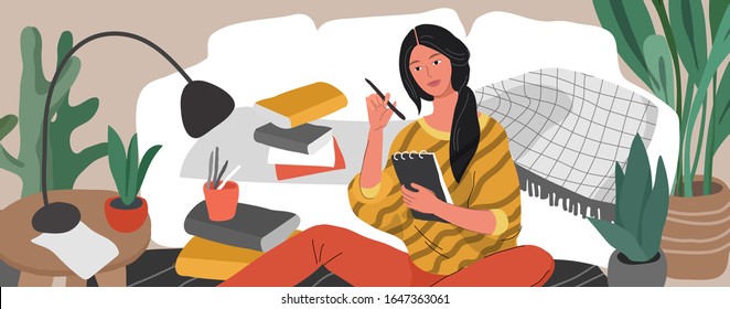 A girl is sitting on the floor surrounded by a laptop, books and papers and writing in note. Woman studying or preparing for exams at home. Teen student studying hard in scandinavian home interior