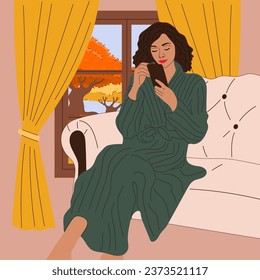 The girl is sitting on the sofa near the window with an autumn view.  Fall season. Hygge concept. Cozy autumn days