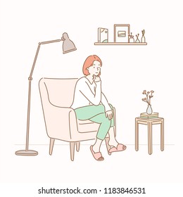 A girl sitting on a sofa in a room with a stand lamp and a small table. hand drawn style vector design illustrations.