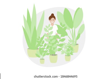 Girl smiling and being happy in her urban jungle between plants. Brunette girl surrounded by green plants.