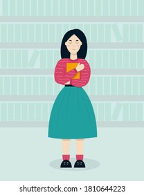 A girl stands and clutches a book in a bookstore.