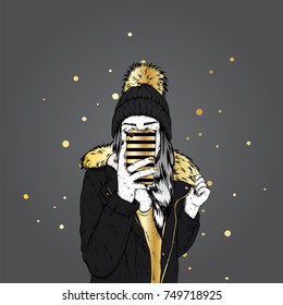 A girl in a stylish down jacket and a beautiful hat with a fluffy bubo. A woman is holding a smartphone and making selfies. Vector illustration. Clothing and accessories, fashion and style.