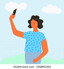 The girl takes pictures of herself on the phone on the street. Selfie on the background of the city.