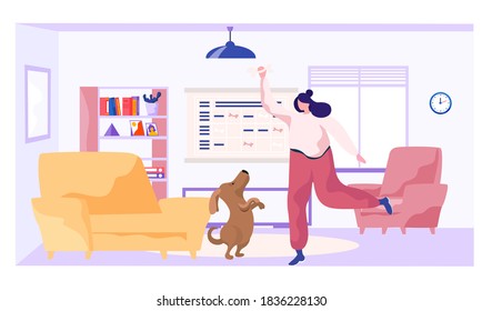 The girl is training the animal at home. The dog is standing on its hind legs. Woman holding bone in her hands. Rehearsal with a pet in the apartment. Dog training calendar on the background