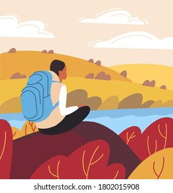 
The girl traveler on the rock sits and looks into the distance. Traveler's rest. Autumn landscape with fields and river