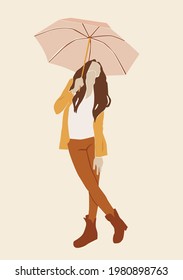 Girl under an umbrella in a jacket and  white T-shirt on the beige isolated background.