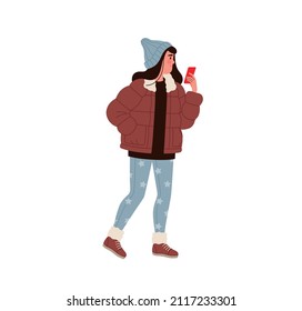 Girl or woman in modern winter clothes with a smartphone in her hands stands on the street. Young woman in a jacket, hat and jeans with a star pattern chatting online