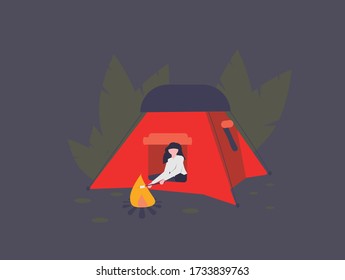 Girl in the woods roasting a s'more on a campfire outside her tent.