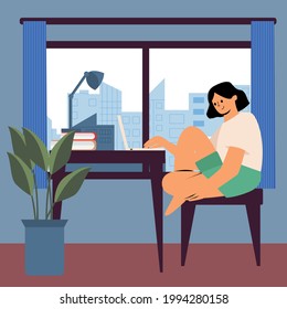 The girl works from home. Freelancer, remote worker, student. A woman is sitting in a room by the window
