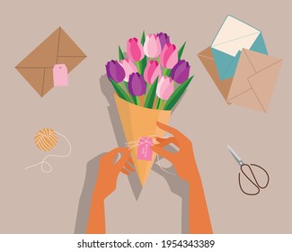 Girl wrapping tulip bouquet to her mother, top view of desk, scissors, envelope, flower. Happy mothers day.Vector illustration in flat style.