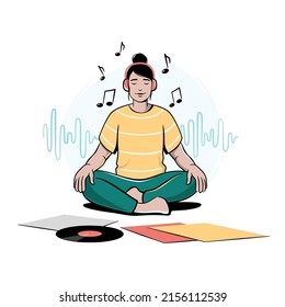 Girl, young woman sitting cross-legged, meditating and listening to music in headphones