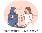 Girls from different ethnicities are talking sitting on couch demonstrating tolerance and lack of cultural prejudice. Woman in muslim clothes is talking to girlfriend of european appearance