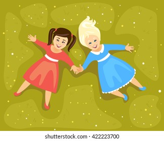 Girls lying on a meadow and holding hands. Friendship. Top view