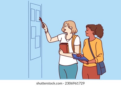 Girls students stand in corridor of college or university near blackboard with lesson schedule or lists of pupils. Two schoolgirls or students with books in their hands read notice on bulletin board