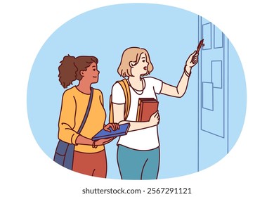 Girls students stand in corridor of college or university near blackboard with lesson schedule or lists of pupils. Two schoolgirls or students with books in their hands read notice on bulletin board