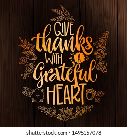 Give Thanks with a Grateful heart - quote. Thanksgiving dinner theme hand drawn lettering phrase. Logo, text design. Pumpkin, leaves, cotton design.  Orange text on dark wood background. 