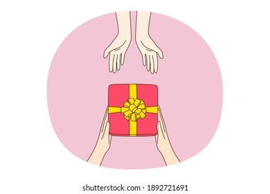 Giving presents, gift, surprise concept. Human hands giving and taking holiday festive present box in red wrapped paper with ribbon, top view. Birthday, anniversary, Christmas new year Valentines day