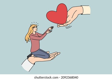 Giving and taking love concept. Young smiling blonde woman sitting on huge hand and taking big red heart from another human hand vector illustration 