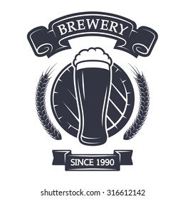 A glass of fresh beer on background barrel. Vintage emblem.
