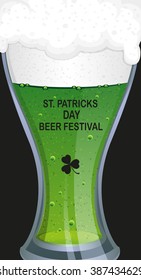 Glass of green beer with bubbles close up on black background. St. Patrick's Day background.