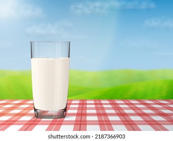 Glass of milk on checkered tablecloth with blurred landscape on background. Cow milk in glass cup against meadow and sky