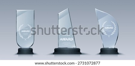 Glass trophy set with elegant laurel wreath engravings on crystal plates. Transparent award collection with unique glass shapes on dark pedestals designs for business or sport recognition ceremonies.